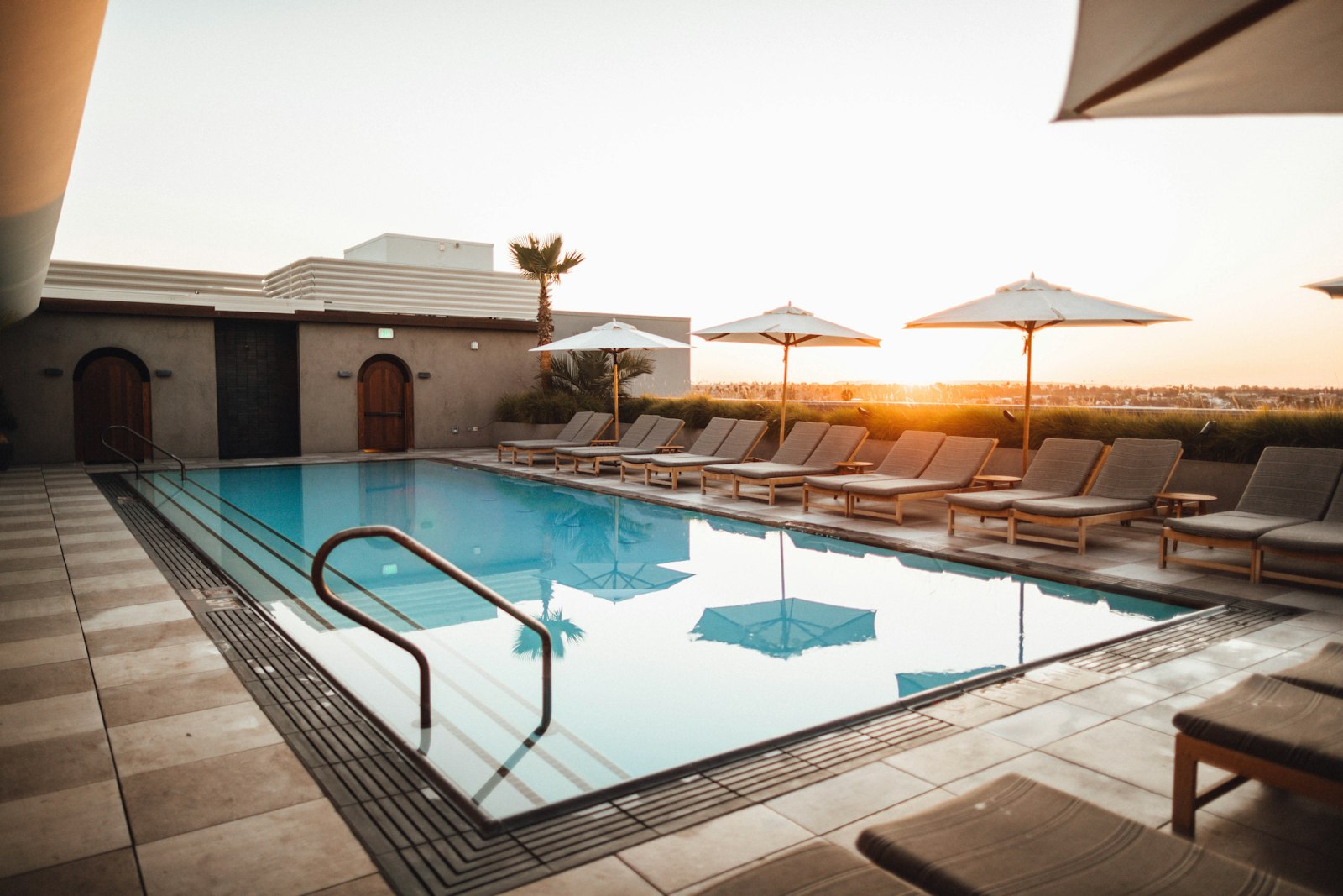 A resort-style pool at golden hour with palm trees and lounge chairs